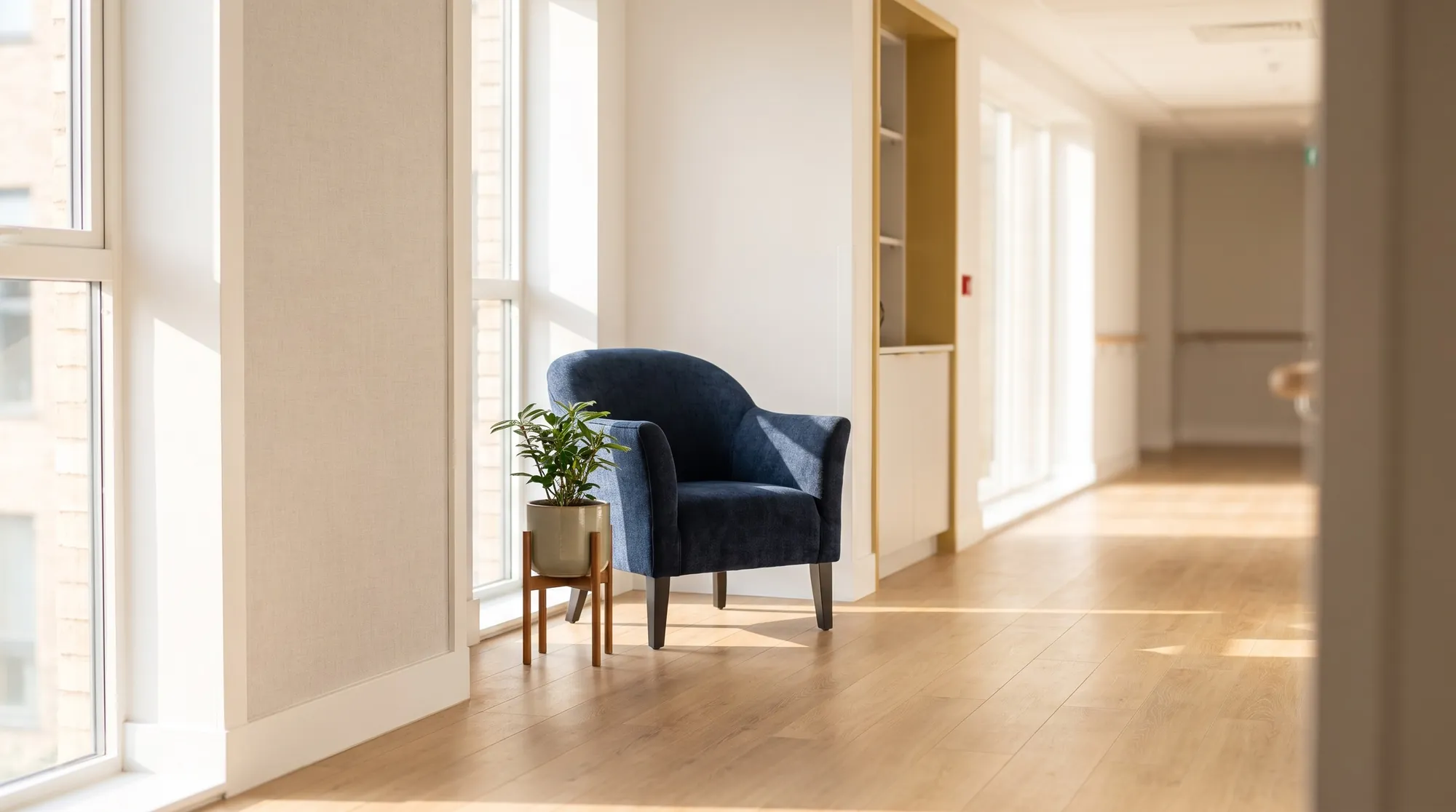 A quiet, empty corridor in a care home with an armchair by the window